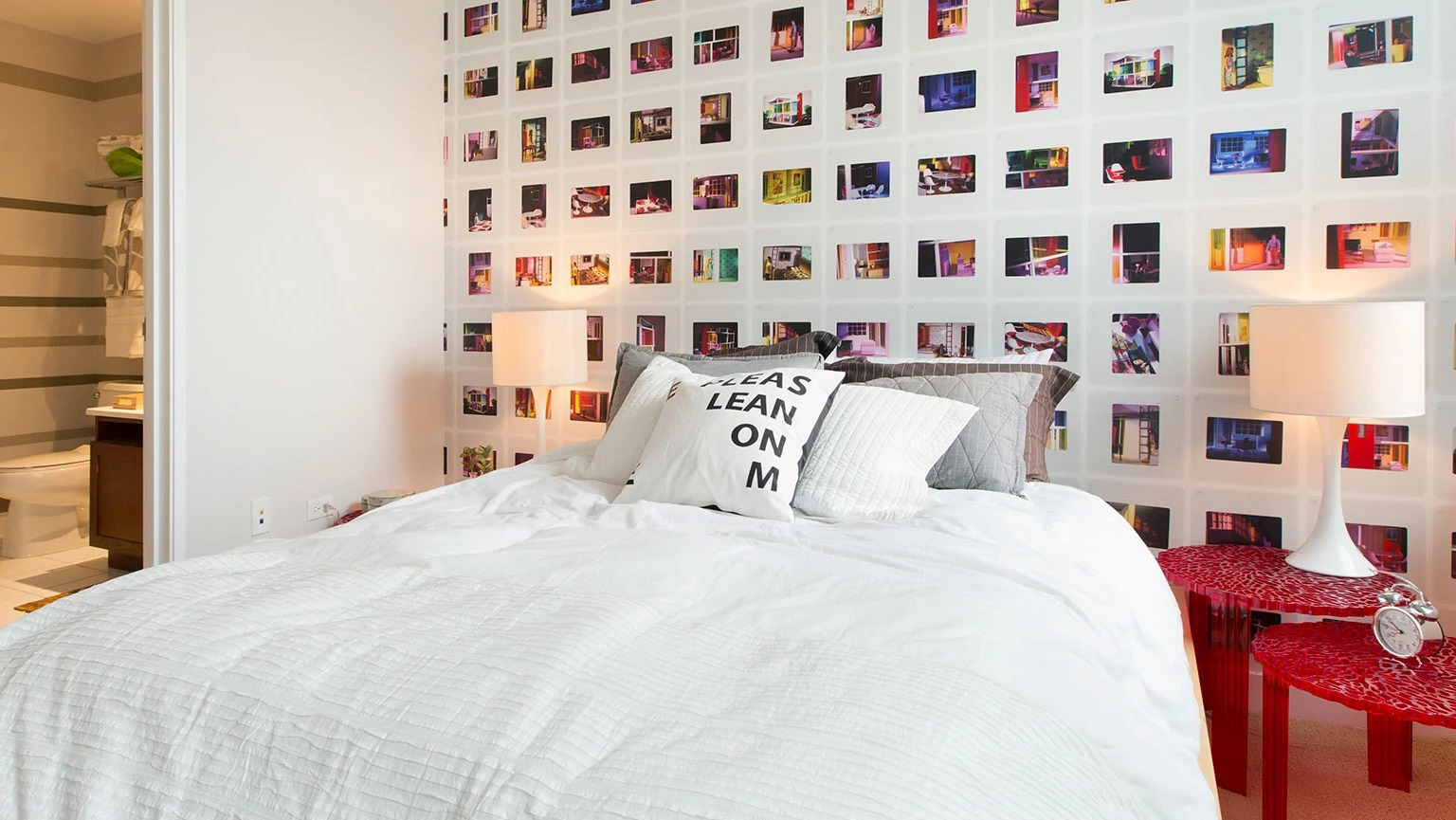 Vibrant bedroom with a unique photo collage accent wall, comfortable bed, and an adjoining modern bathroom at MDA Apartments in Chicago