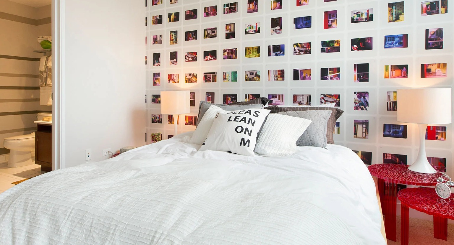 Vibrant bedroom with a unique photo collage accent wall, comfortable bed, and an adjoining modern bathroom at MDA Apartments in Chicago