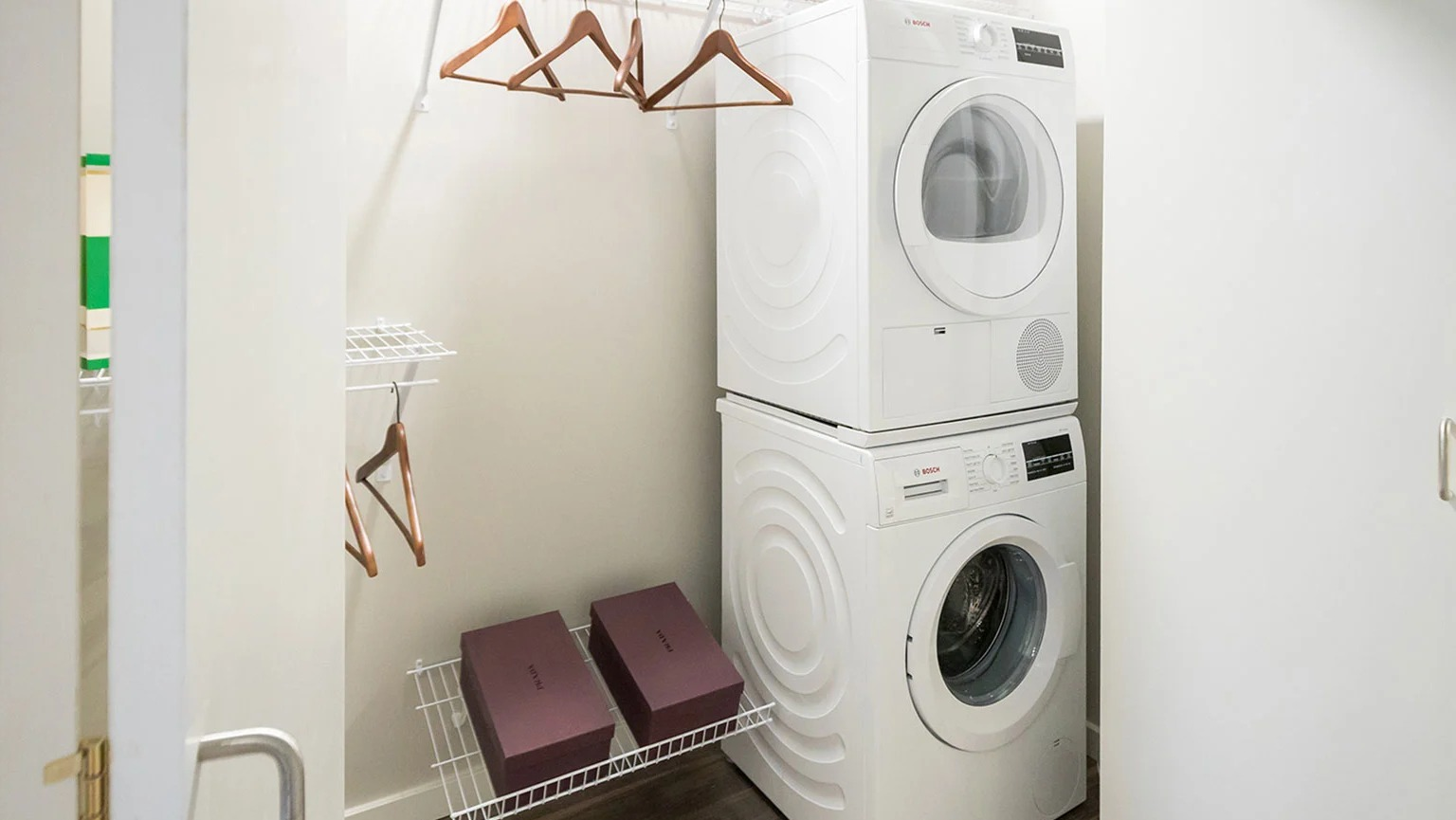 Convenient in-unit laundry closet with a stacked washer and dryer, plus shelving for storage at MDA Apartments in Chicago