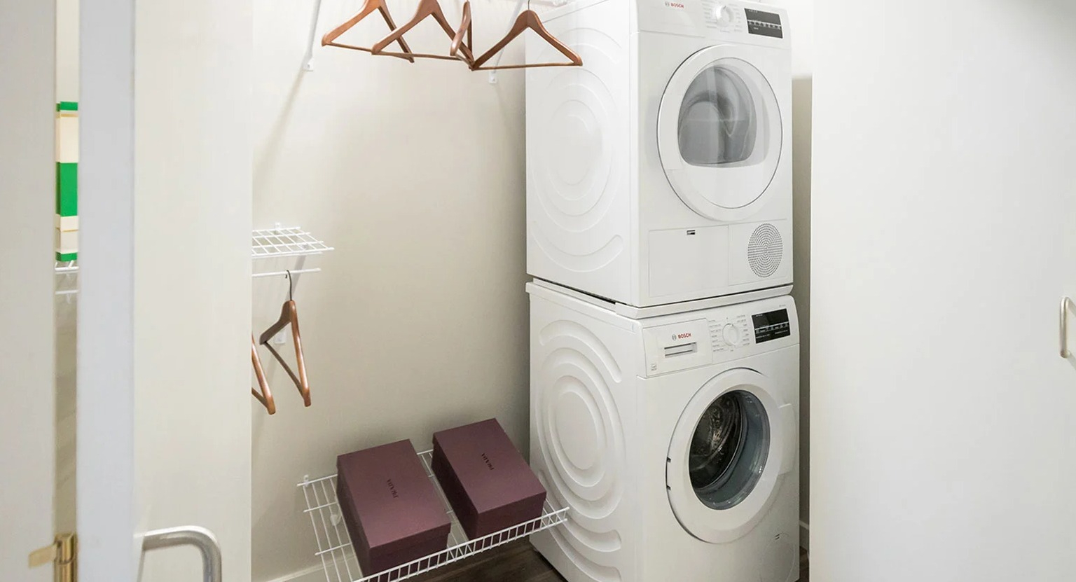 Convenient in-unit laundry closet with a stacked washer and dryer, plus shelving for storage at MDA Apartments in Chicago