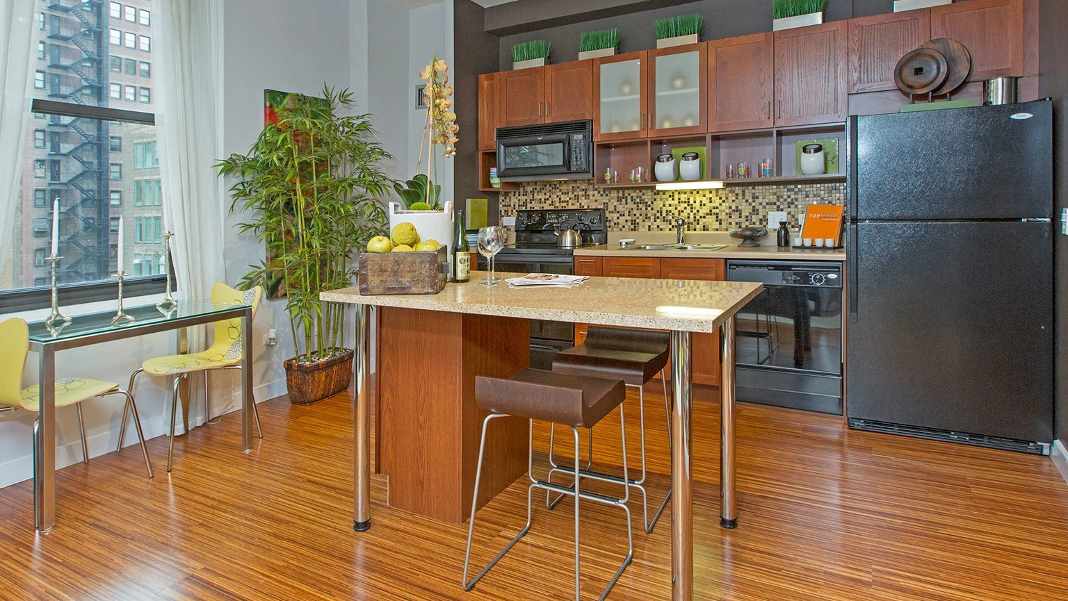 Spacious kitchen with an island, dark appliances, wood cabinets, and a charming dining area by the window at MDA Apartments in Chicago