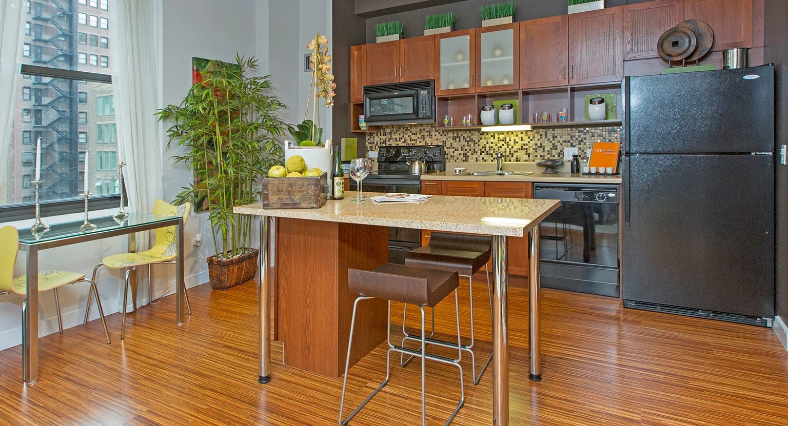 Spacious kitchen with an island, dark appliances, wood cabinets, and a charming dining area by the window at MDA Apartments in Chicago