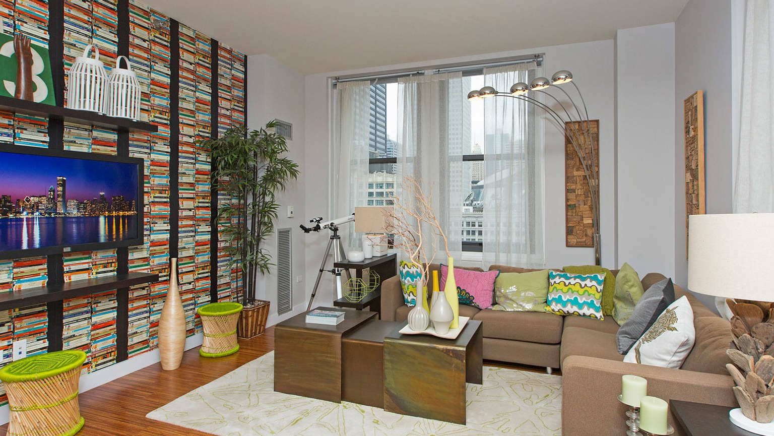 Modern living room with a colorful accent wall, flat-screen TV, comfortable sofa, and abundant natural light at MDA Apartments in Chicago