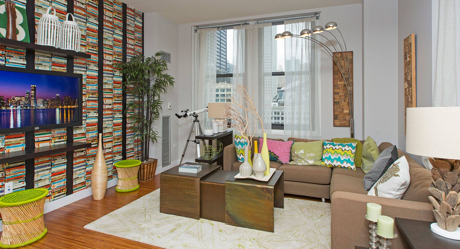 Modern living room with a colorful accent wall, flat-screen TV, comfortable sofa, and abundant natural light at MDA Apartments in Chicago