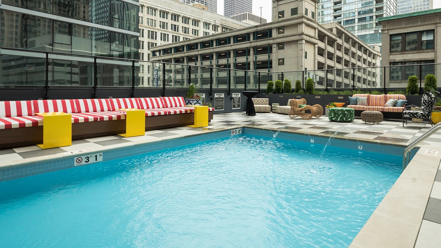 Inviting outdoor swimming pool surrounded by comfortable lounge seating and city buildings at MDA Apartments in Chicago