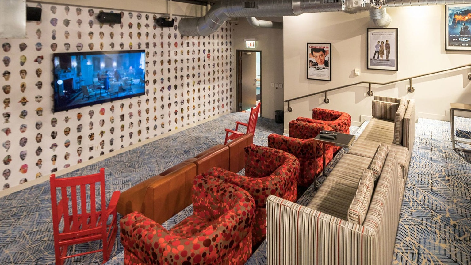 Vibrant resident lounge with a large TV, comfortable red and striped seating, and unique wall decor at MDA Apartments in Chicago