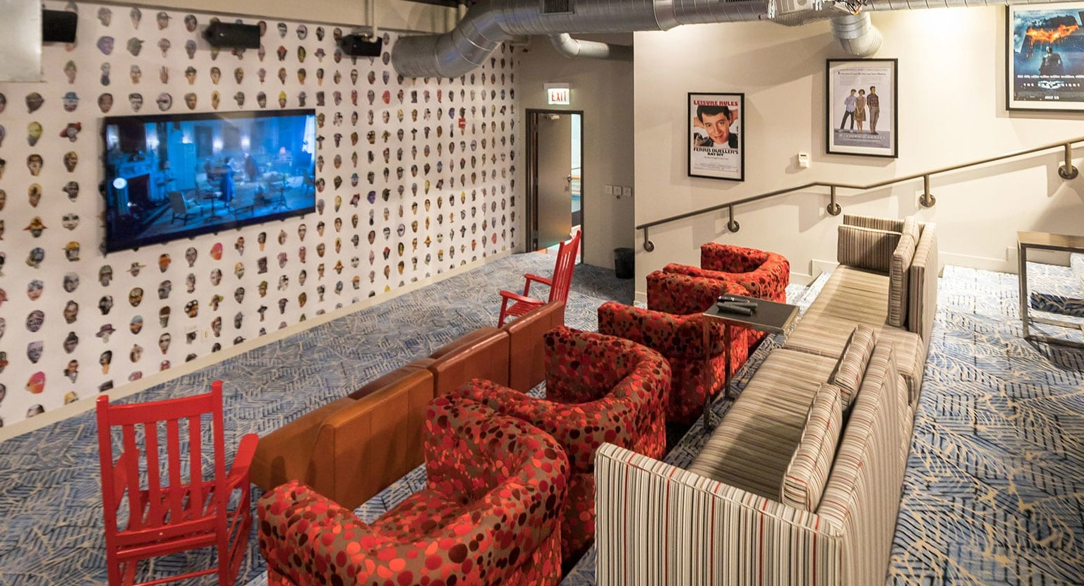 Vibrant resident lounge with a large TV, comfortable red and striped seating, and unique wall decor at MDA Apartments in Chicago