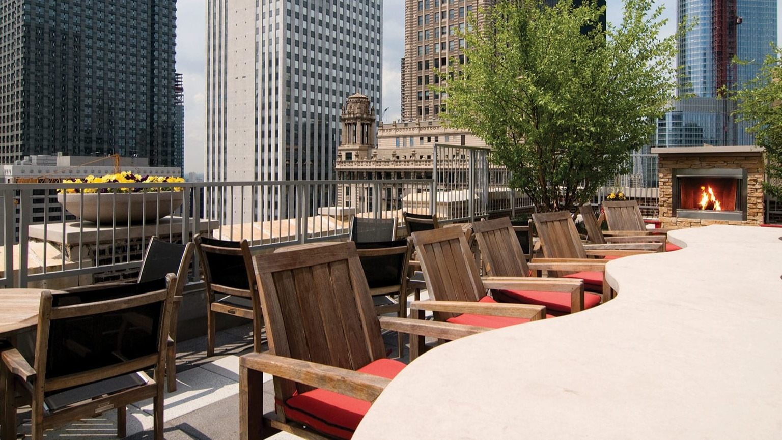 Stunning rooftop lounge with outdoor seating, a modern fireplace, and panoramic Chicago city views at MDA Apartments