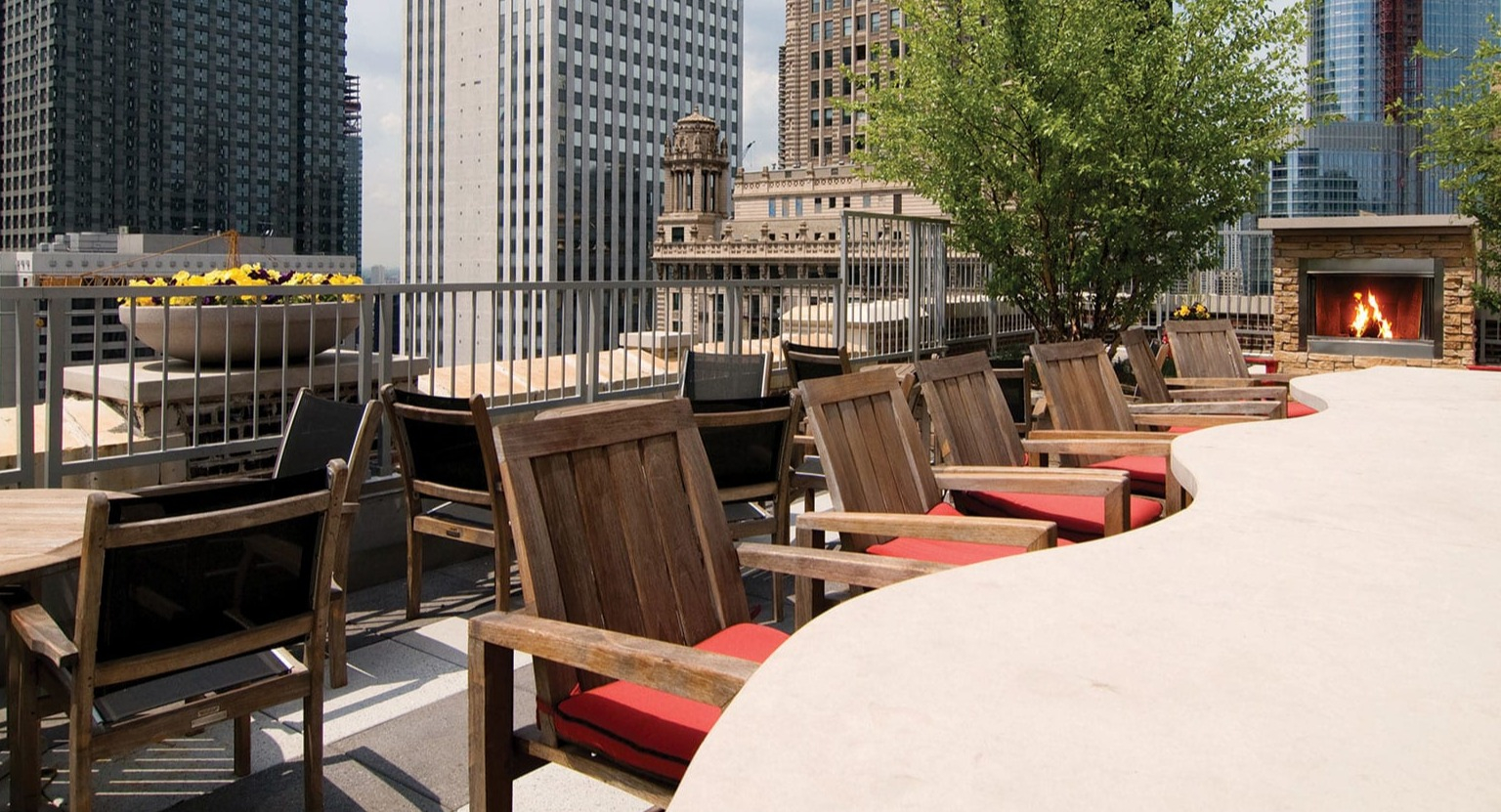 Stunning rooftop lounge with outdoor seating, a modern fireplace, and panoramic Chicago city views at MDA Apartments
