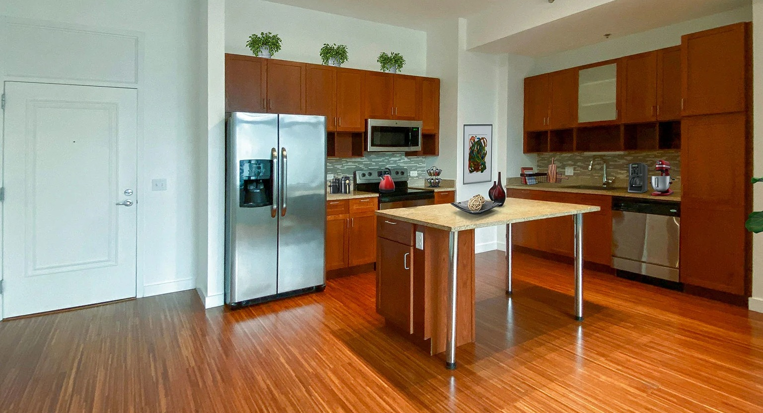 Expansive kitchen with wood cabinets, stainless steel appliances, a center island, and gleaming hardwood floors at MDA Apartments in Chicago
