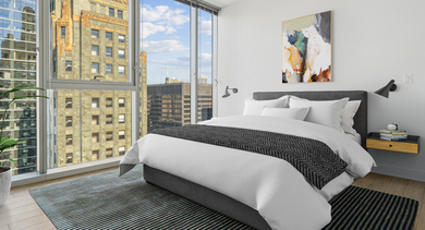 Modern bedroom with a queen-sized bed, sleek nightstands, and stunning floor-to-ceiling windows offering city views at MILA Luxury Apartments in Chicago