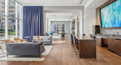 Spacious communal lounge featuring a stylish bar area, comfortable seating, and large windows at MILA Luxury Apartments in Chicago