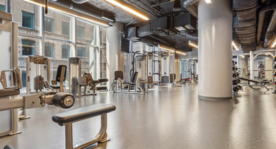 State-of-the-art fitness center with a wide array of weight machines, free weights, and cardio equipment at MILA Luxury Apartments in Chicago