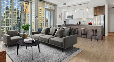 Contemporary kitchen and living area featuring stainless steel appliances, a breakfast bar, and comfortable seating at MILA Luxury Apartments in Chicago