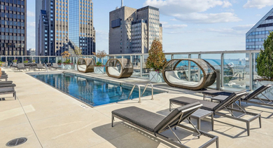 Stunning rooftop swimming pool surrounded by modern lounge chairs, daybeds, and cabanas, with city views at MILA Luxury Apartments in Chicago