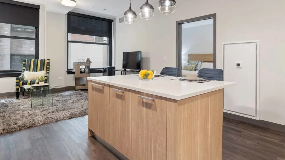 Contemporary kitchen featuring a large island, pendant lighting, and an open view into the inviting living room at Millennium on LaSalle in Chicago