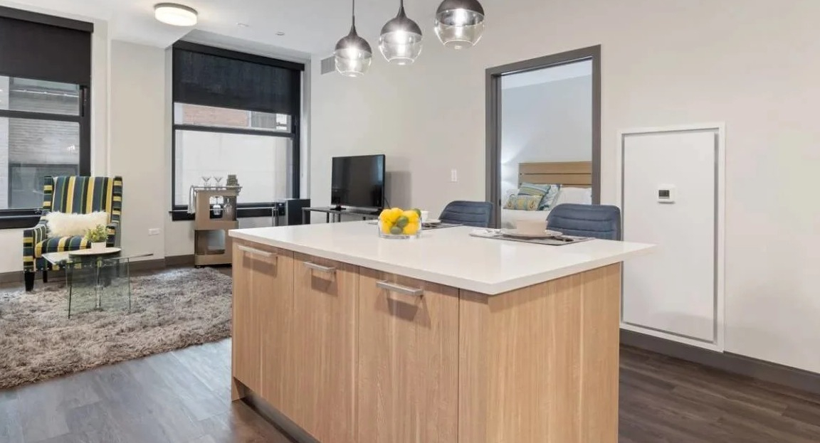 Contemporary kitchen featuring a large island, pendant lighting, and an open view into the inviting living room at Millennium on LaSalle in Chicago