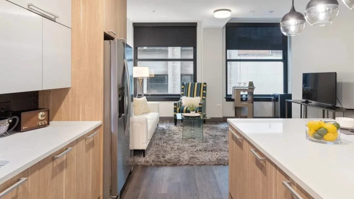 Modern kitchen with light wood cabinetry, white countertops, and an open layout flowing into the living room at Millennium on LaSalle in Chicago