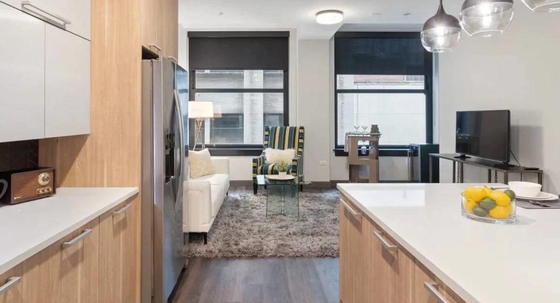 Modern kitchen with light wood cabinetry, white countertops, and an open layout flowing into the living room at Millennium on LaSalle in Chicago