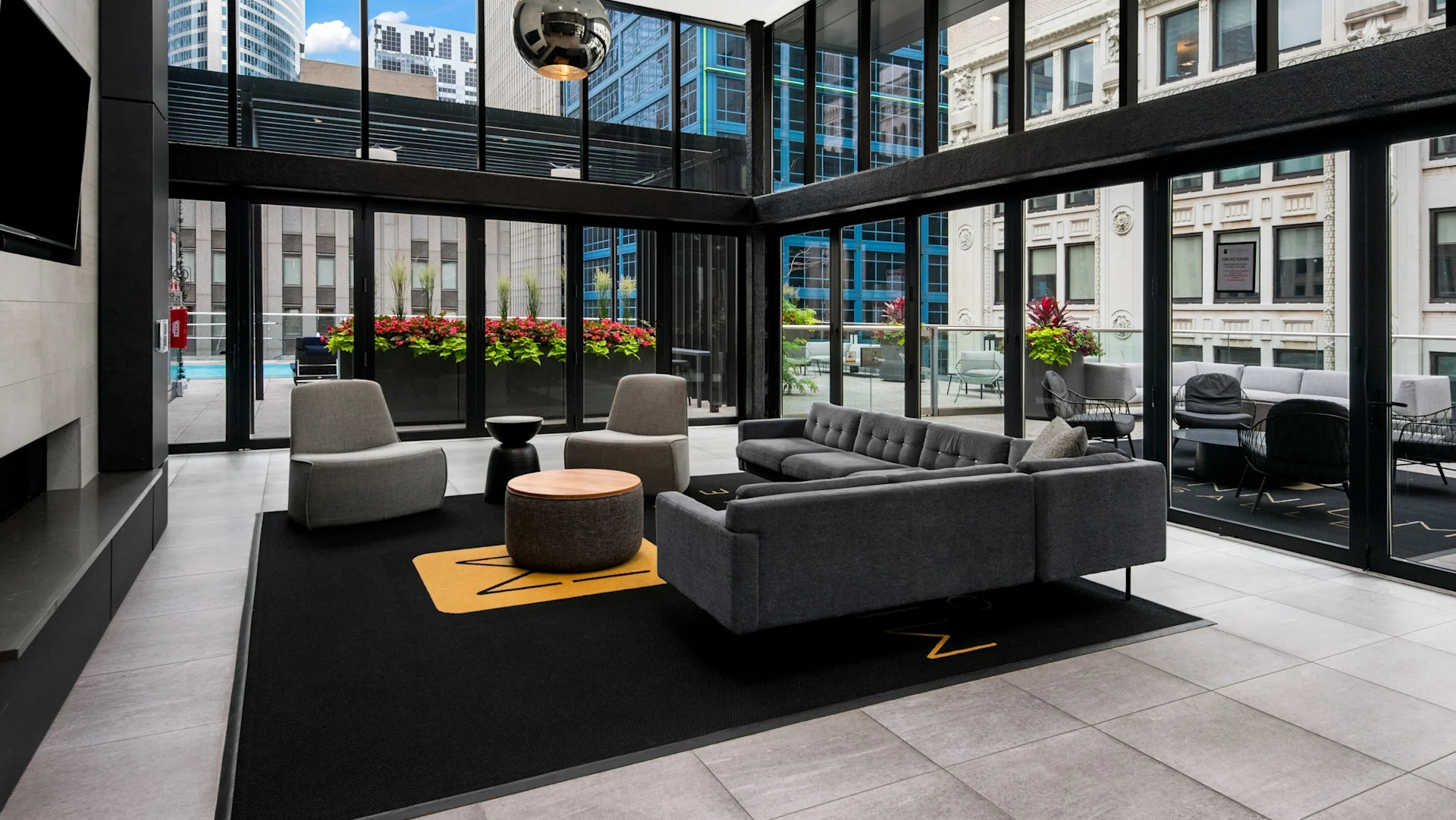Contemporary lobby lounge with plush sofas, a fireplace, and large windows offering views of the pool deck at Millennium on LaSalle in Chicago