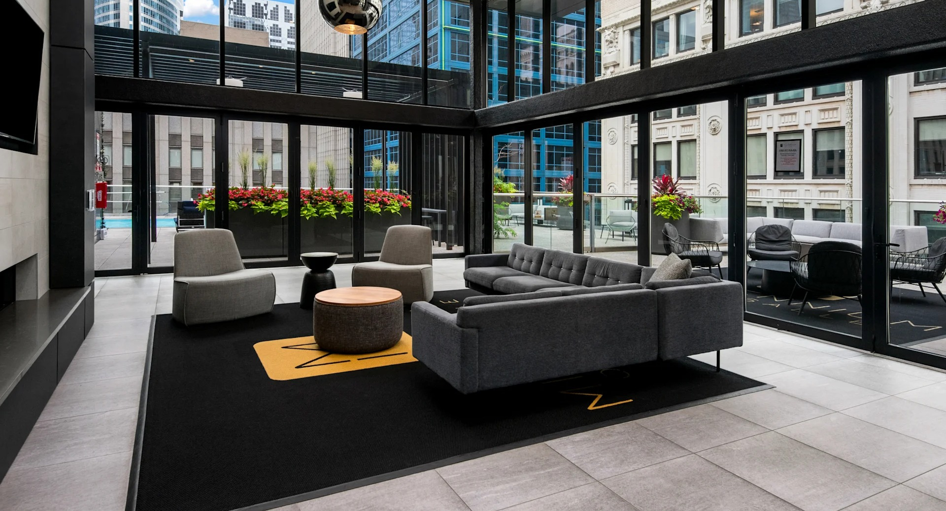 Contemporary lobby lounge with plush sofas, a fireplace, and large windows offering views of the pool deck at Millennium on LaSalle in Chicago