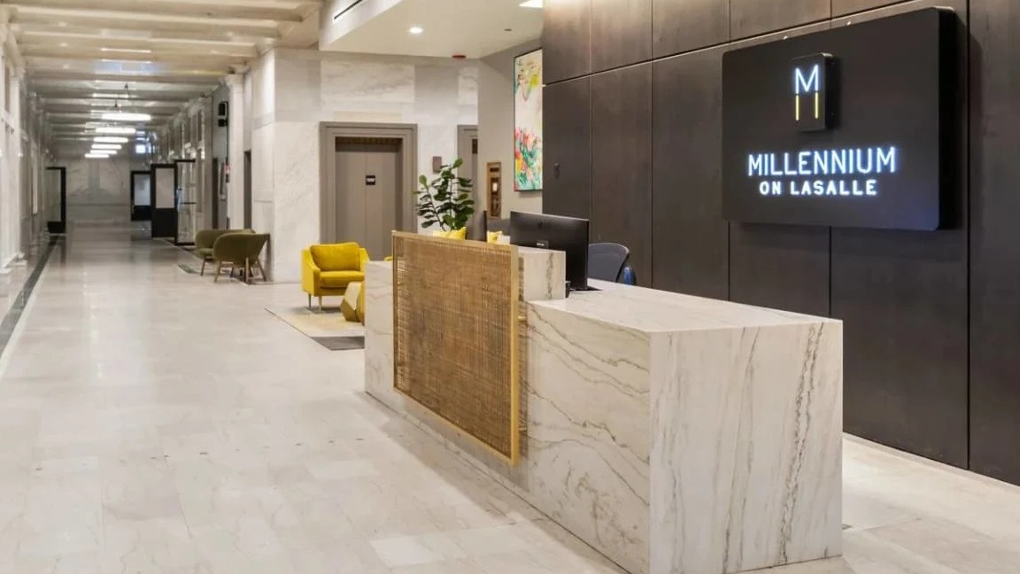 Elegant lobby with a modern reception desk, stylish lighting, and a long hallway leading to elevators at Millennium on LaSalle in Chicago