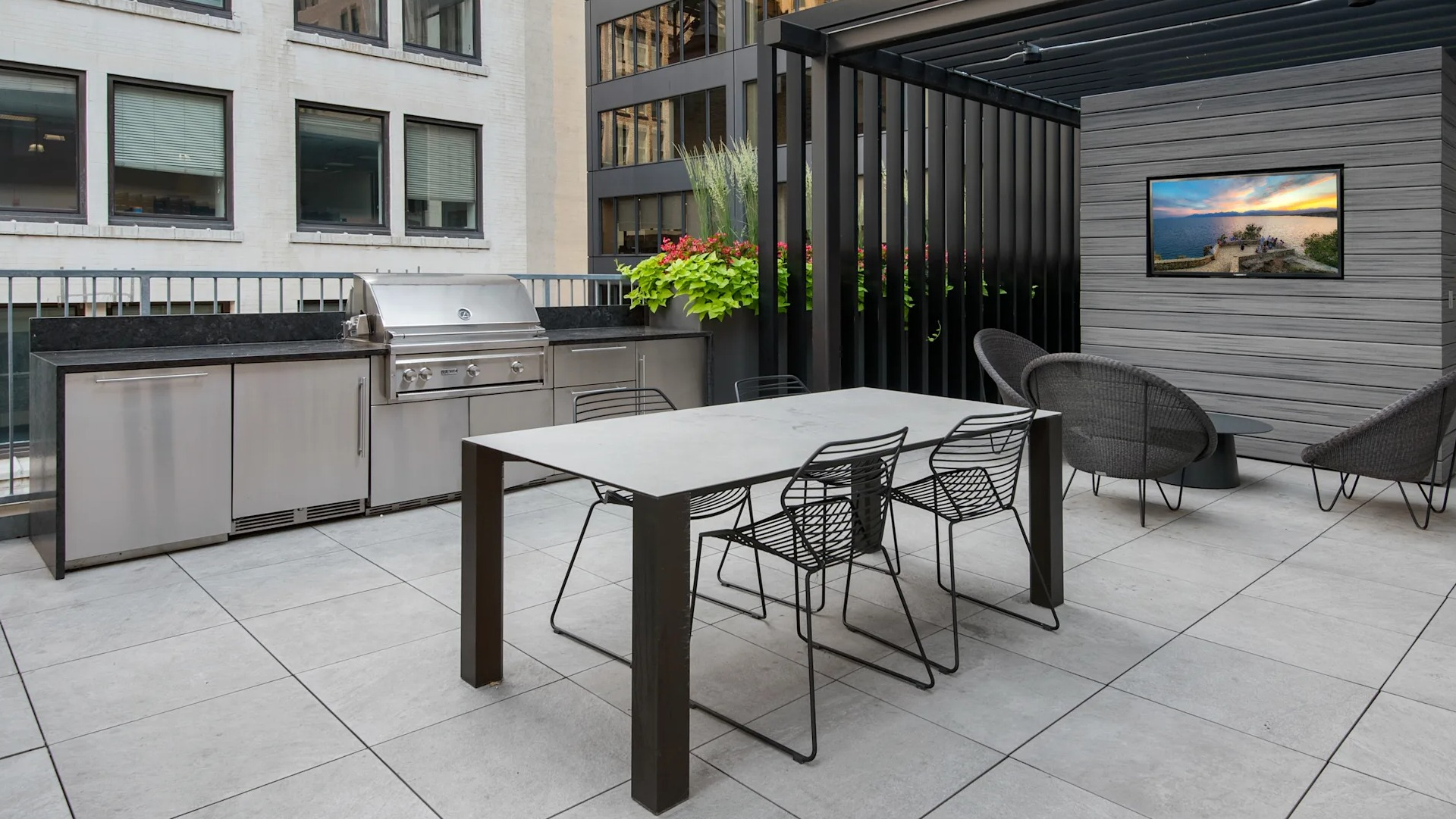 Modern outdoor grilling and dining area with a long table, chairs, and a sleek barbecue station at Millennium on LaSalle in Chicago