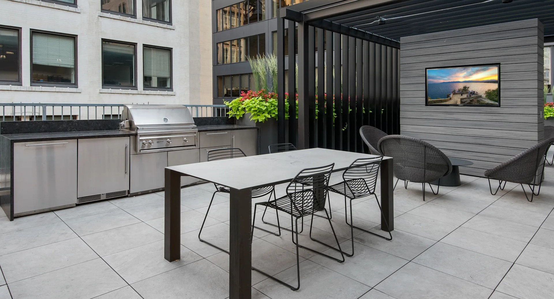 Modern outdoor grilling and dining area with a long table, chairs, and a sleek barbecue station at Millennium on LaSalle in Chicago