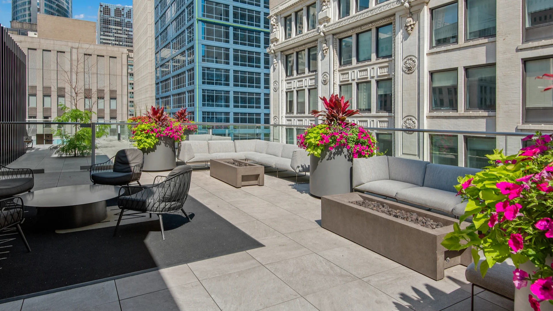 Stylish outdoor lounge with comfortable sofas, chairs, and modern fire pits, surrounded by lush plants at Millennium on LaSalle in Chicago