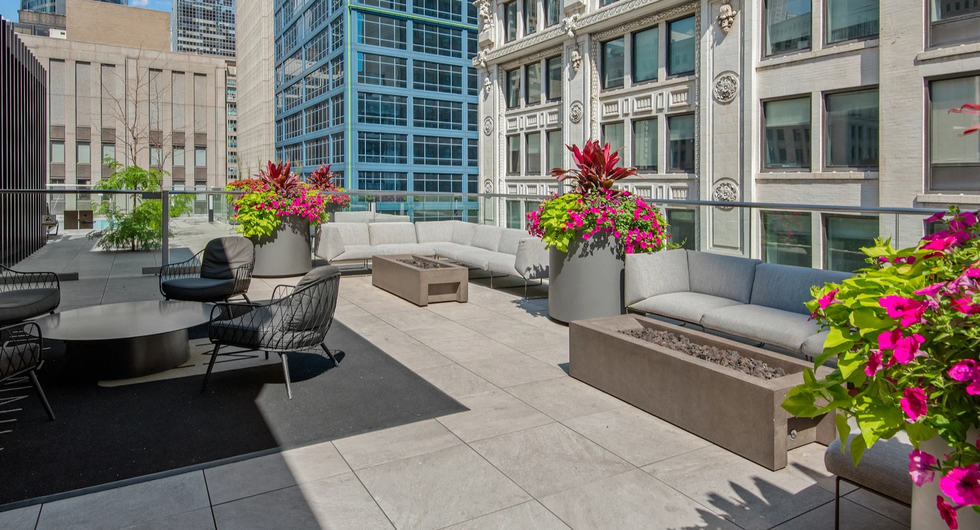 Stylish outdoor lounge with comfortable sofas, chairs, and modern fire pits, surrounded by lush plants at Millennium on LaSalle in Chicago