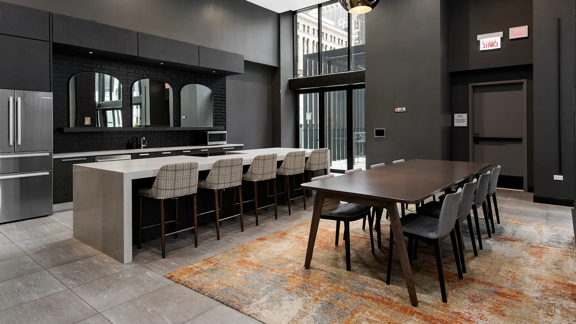 Spacious resident kitchen with a large island, bar seating, and a long dining table, all in a modern dark aesthetic at Millennium on LaSalle in Chicago