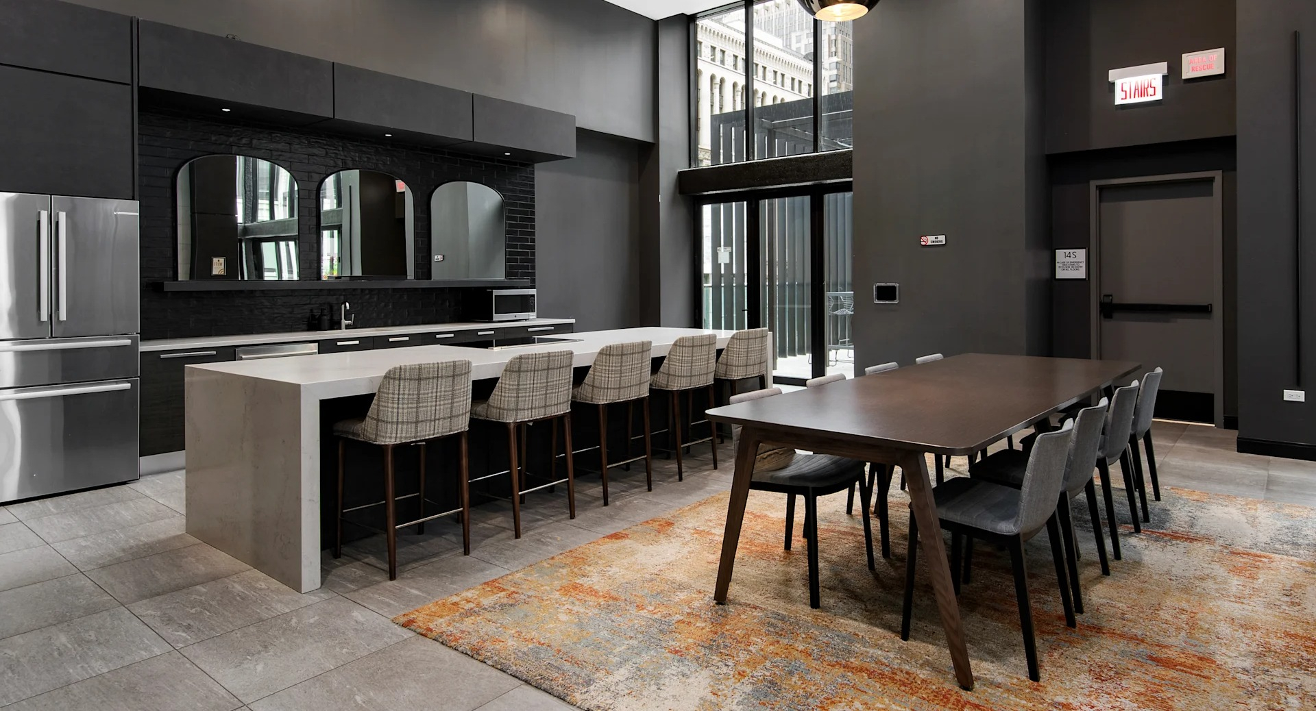 Spacious resident kitchen with a large island, bar seating, and a long dining table, all in a modern dark aesthetic at Millennium on LaSalle in Chicago