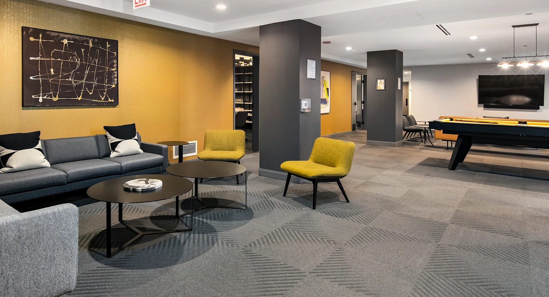Modern resident lounge with cozy sofas, bright chairs, a pool table, and unique art at Millennium on LaSalle in Chicago