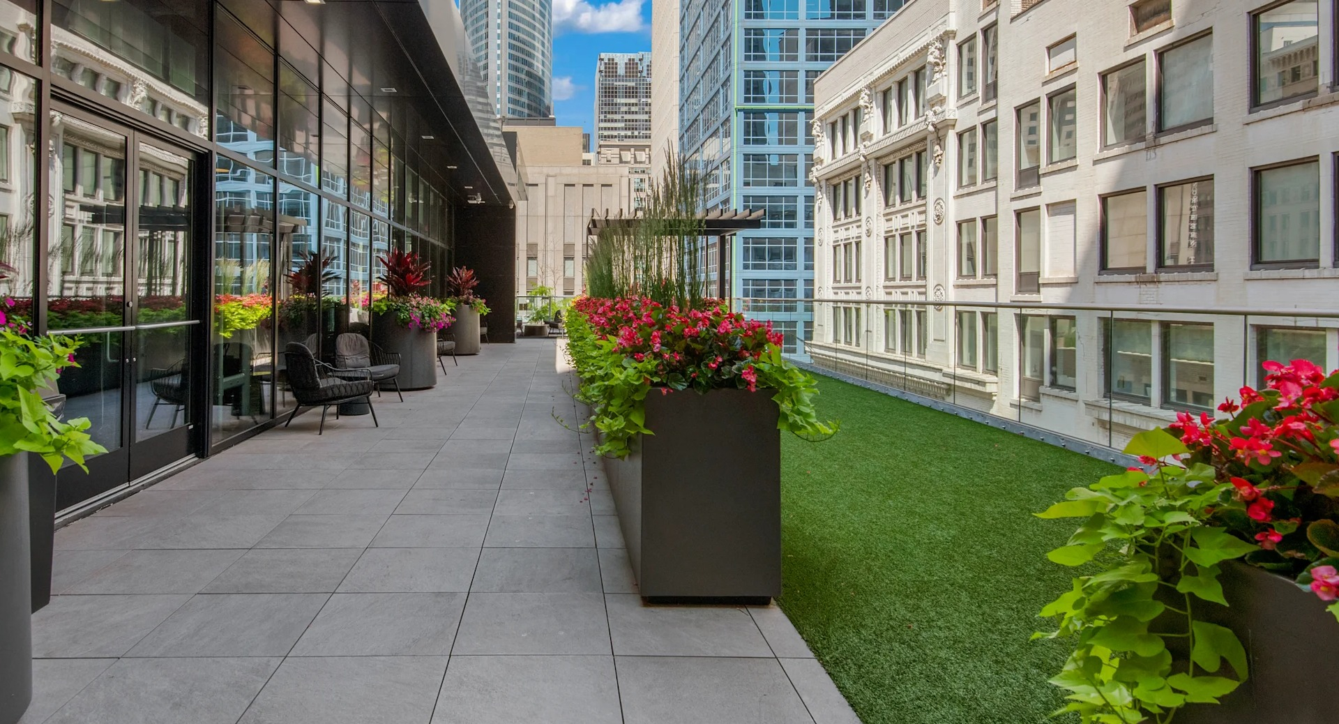 Landscaped rooftop pathway with potted plants and seating, leading alongside modern glass buildings at Millennium on LaSalle in Chicago