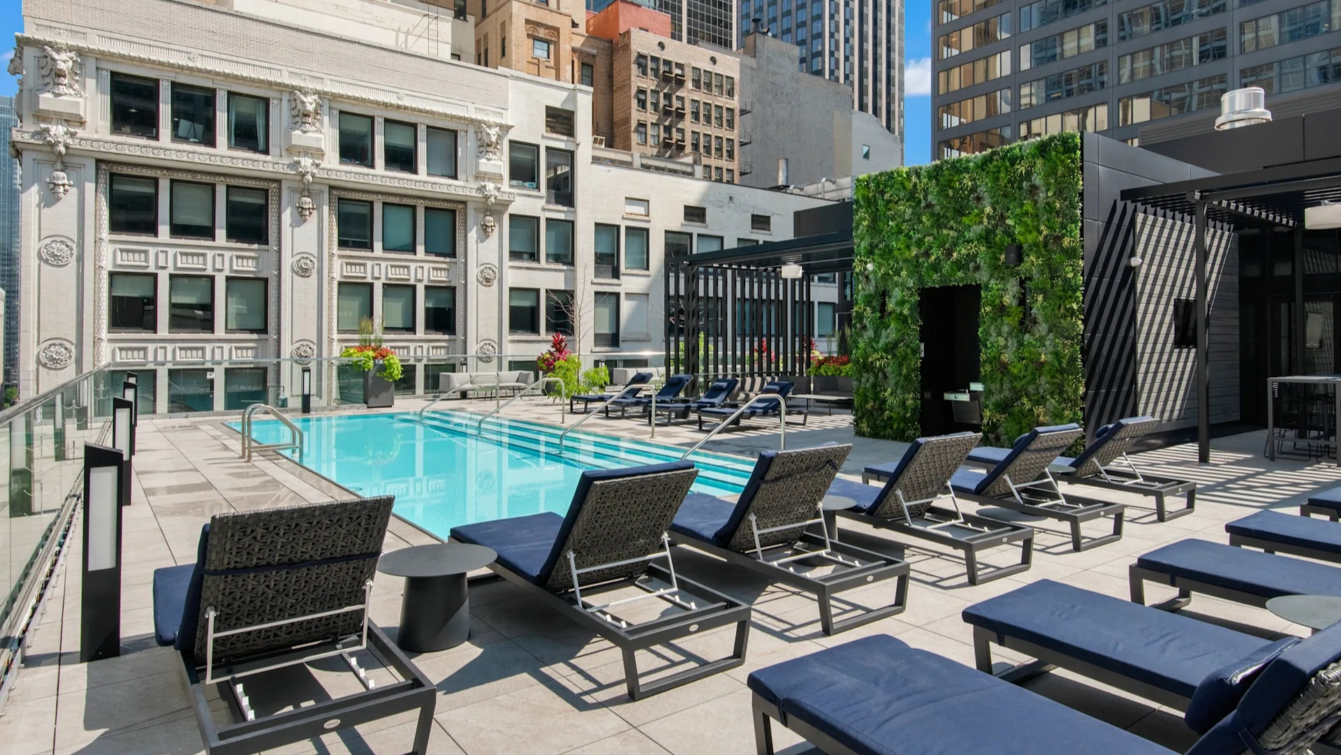 Sparkling rooftop swimming pool with lounge chairs and cabanas, surrounded by urban buildings at Millennium on LaSalle in Chicago