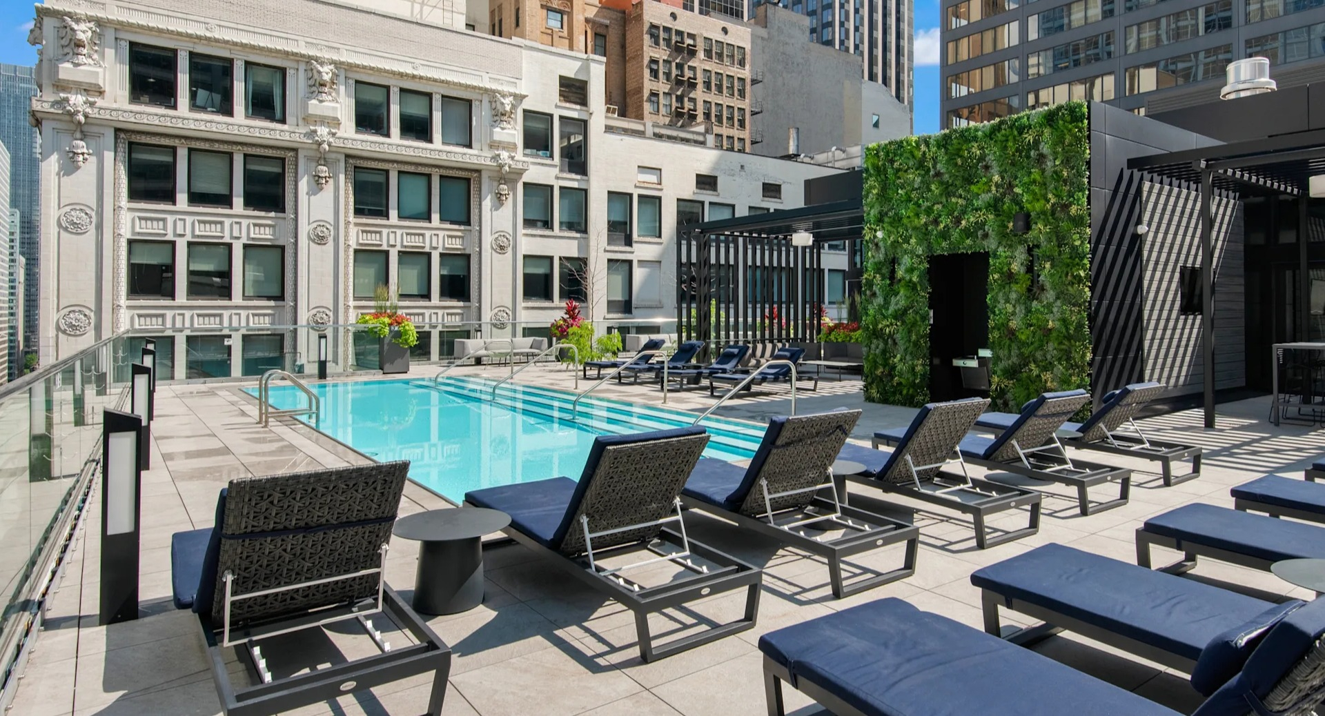 Sparkling rooftop swimming pool with lounge chairs and cabanas, surrounded by urban buildings at Millennium on LaSalle in Chicago