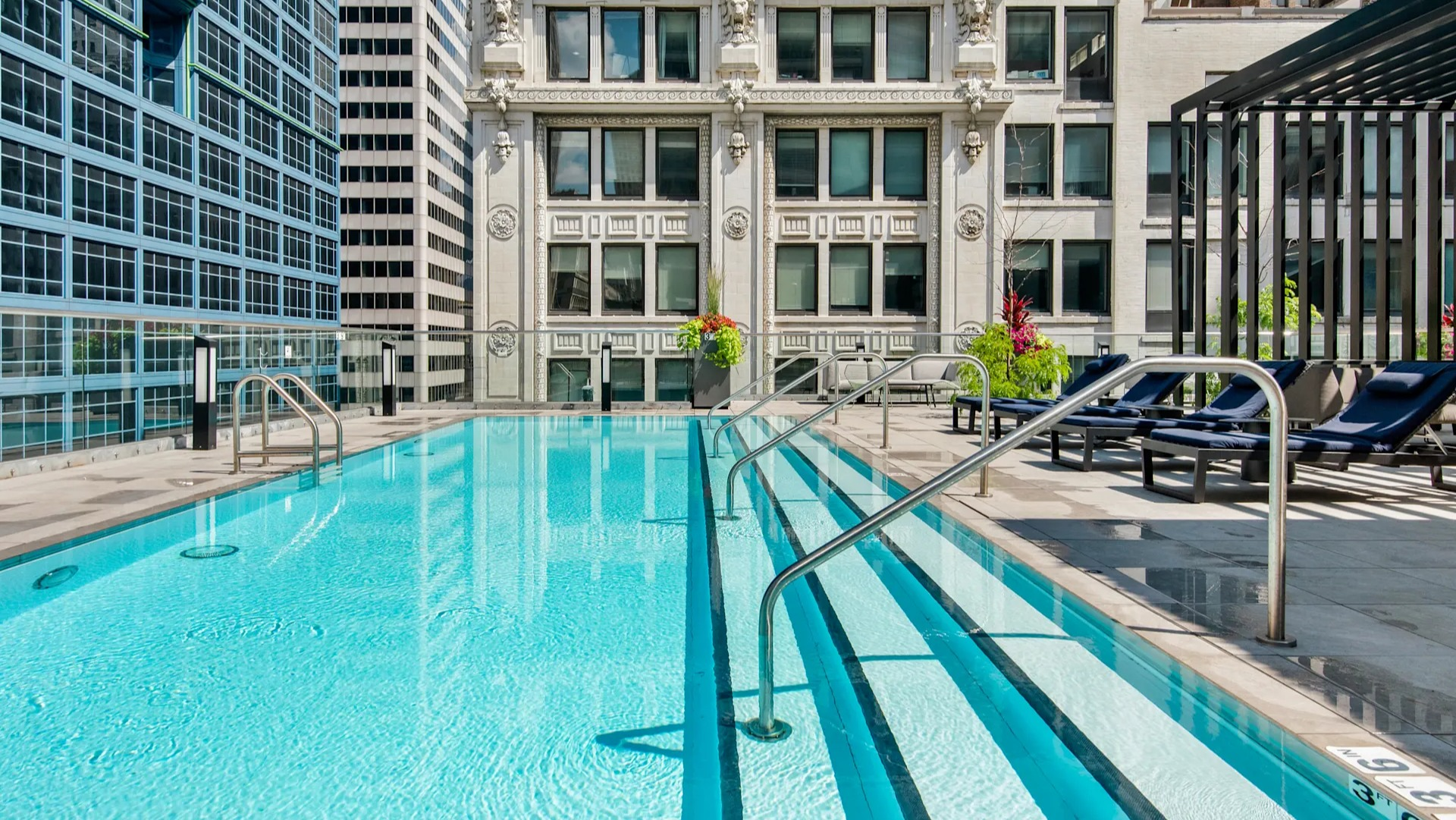 Close-up view of the pristine swimming pool with steps, surrounded by impressive city buildings at Millennium on LaSalle in Chicago