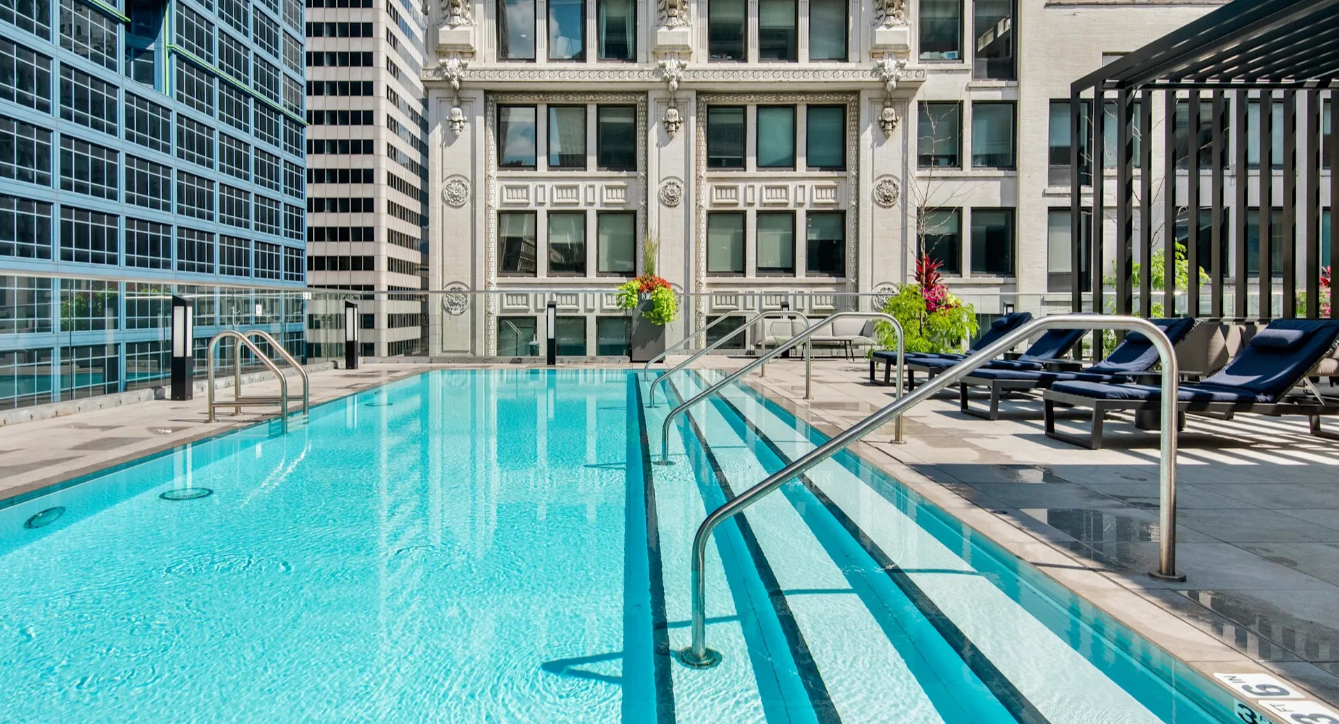 Close-up view of the pristine swimming pool with steps, surrounded by impressive city buildings at Millennium on LaSalle in Chicago