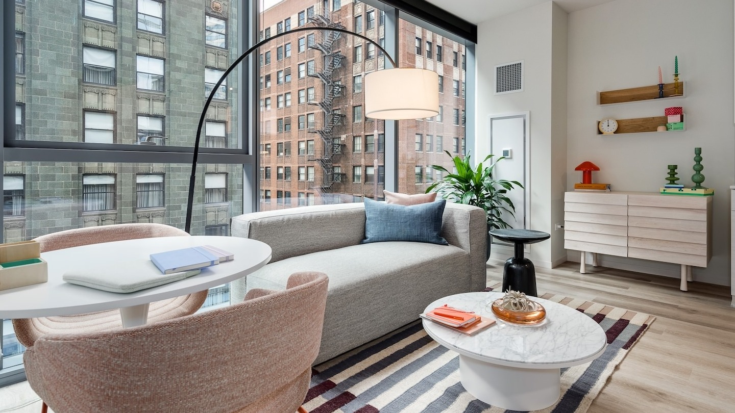 Bright apartment living area with a cozy sofa, dining space, and large windows showcasing urban views at Millie on Michigan Chicago