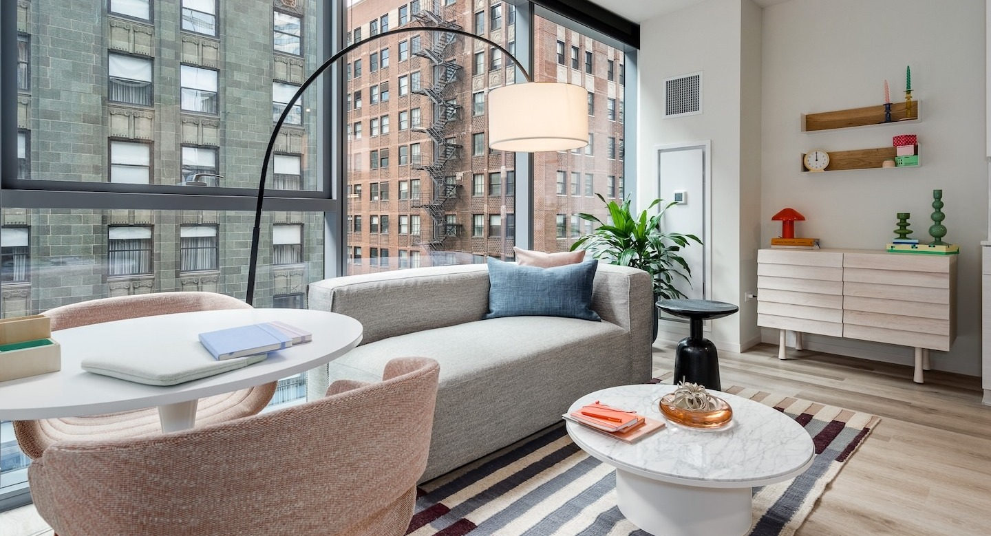 Bright apartment living area with a cozy sofa, dining space, and large windows showcasing urban views at Millie on Michigan Chicago