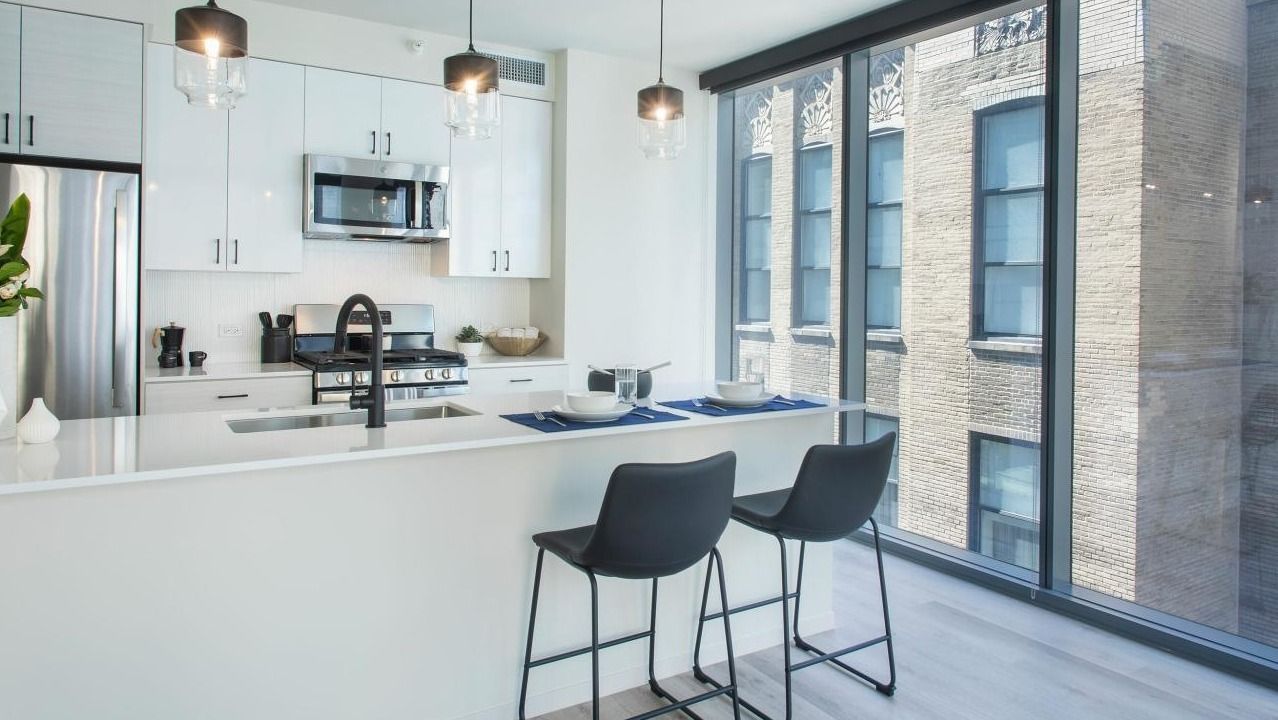 Bright kitchen and dining area with an island, modern appliances, and large windows at Millie on Michigan in Chicago