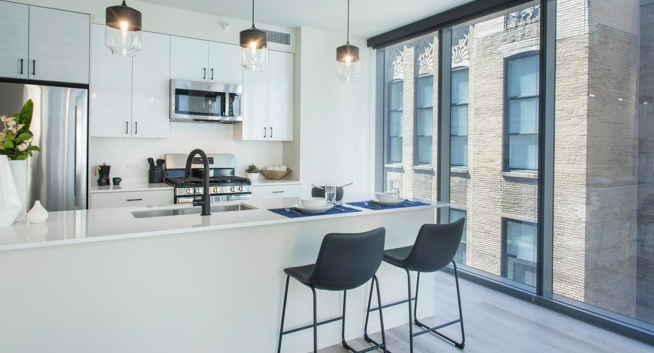 Bright kitchen and dining area with an island, modern appliances, and large windows at Millie on Michigan in Chicago