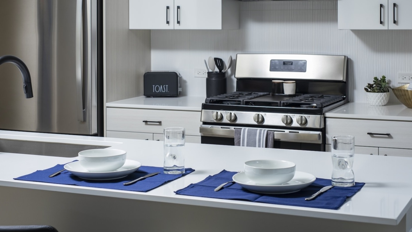 Contemporary kitchen with a dining island, stainless steel appliances, and place settings at Millie on Michigan in Chicago