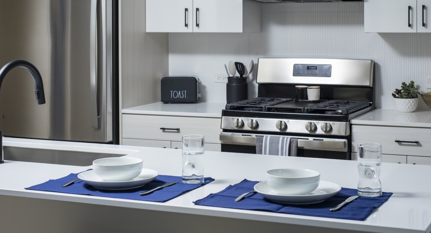 Contemporary kitchen with a dining island, stainless steel appliances, and place settings at Millie on Michigan in Chicago