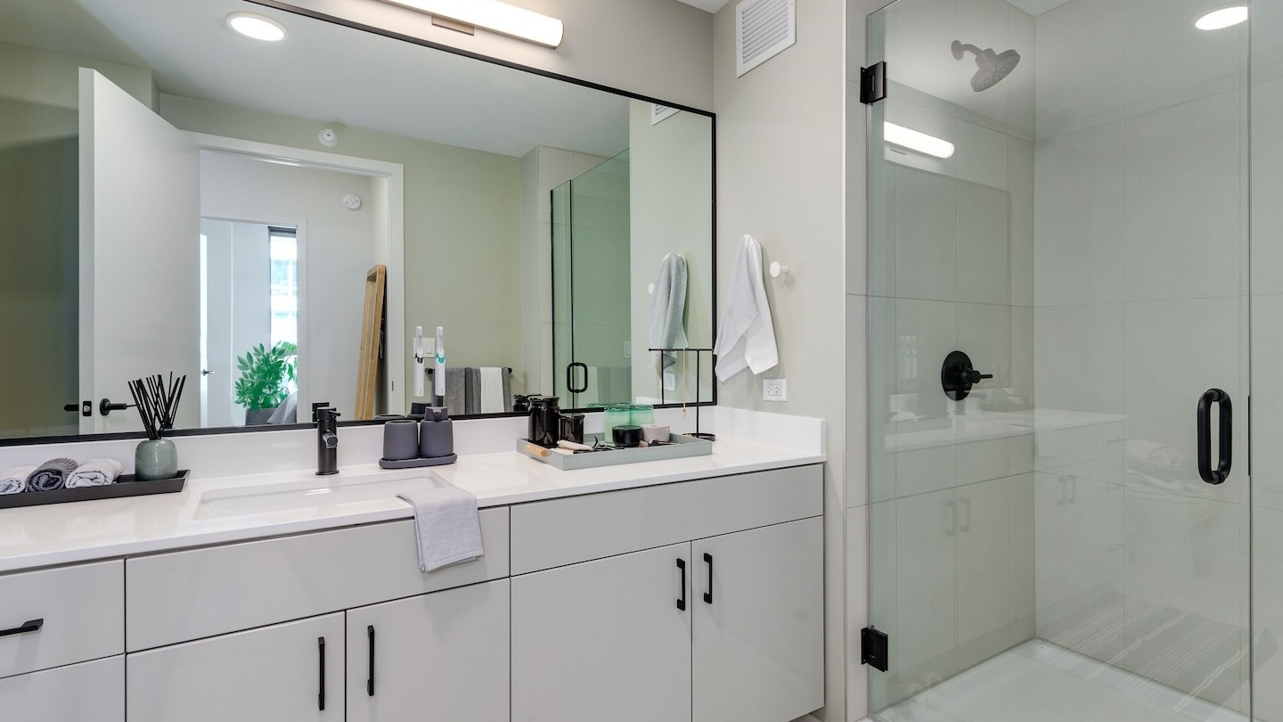 Luxurious bathroom featuring a large double vanity, lighted mirror, and a glass-enclosed shower at Millie on Michigan Chicago