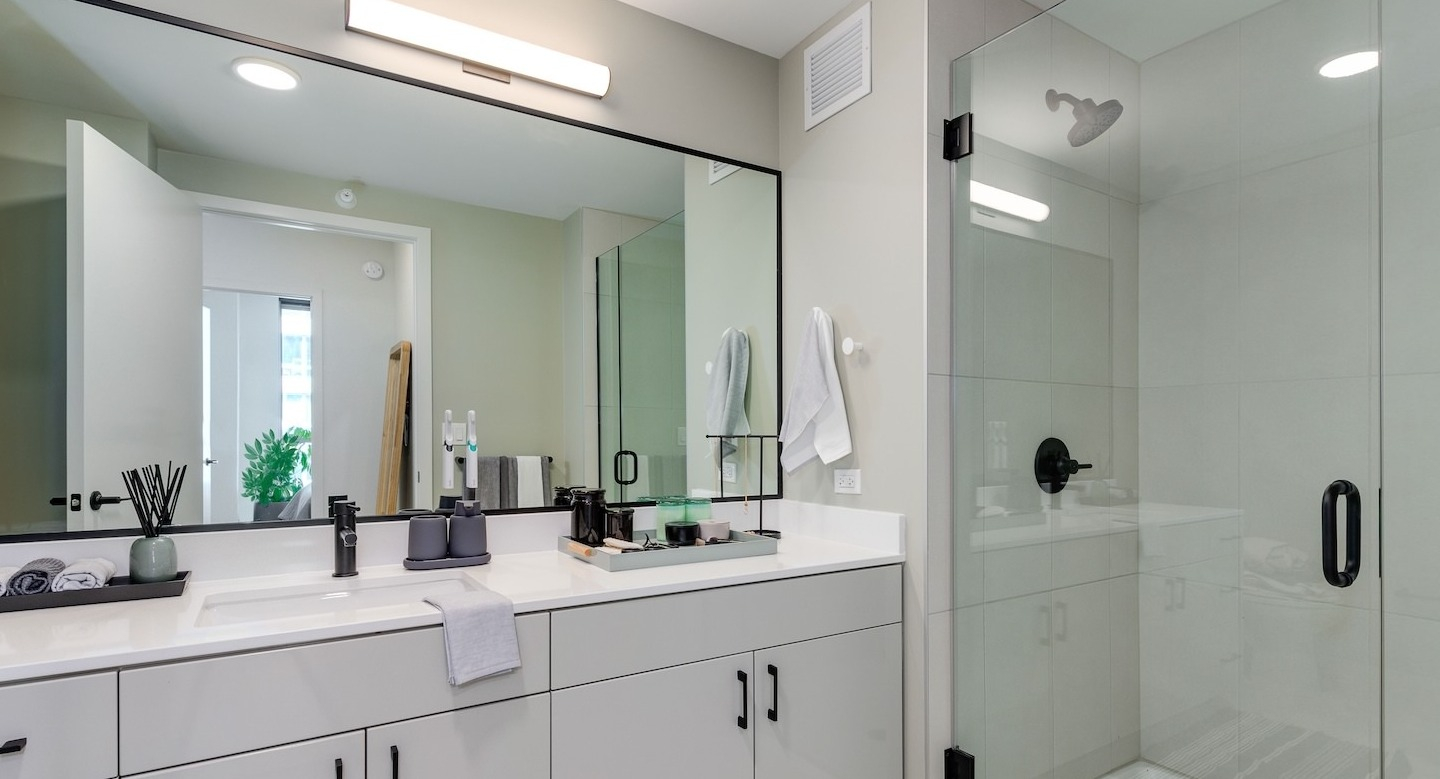 Luxurious bathroom featuring a large double vanity, lighted mirror, and a glass-enclosed shower at Millie on Michigan Chicago
