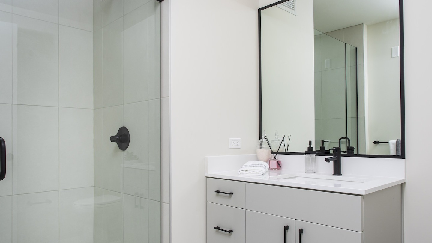 Modern bathroom at Millie on Michigan in Chicago, featuring a glass shower, black fixtures, and a clean, spacious design