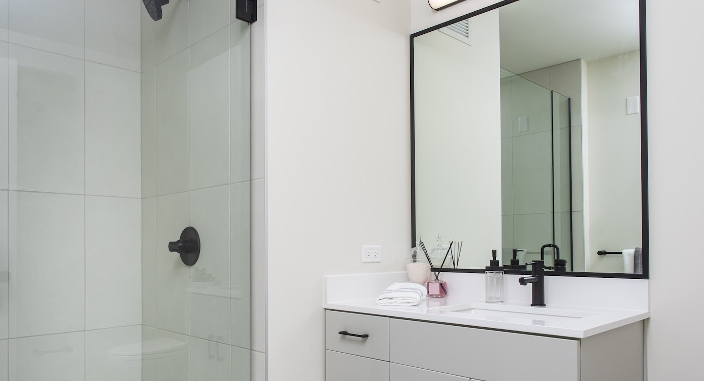 Modern bathroom at Millie on Michigan in Chicago, featuring a glass shower, black fixtures, and a clean, spacious design