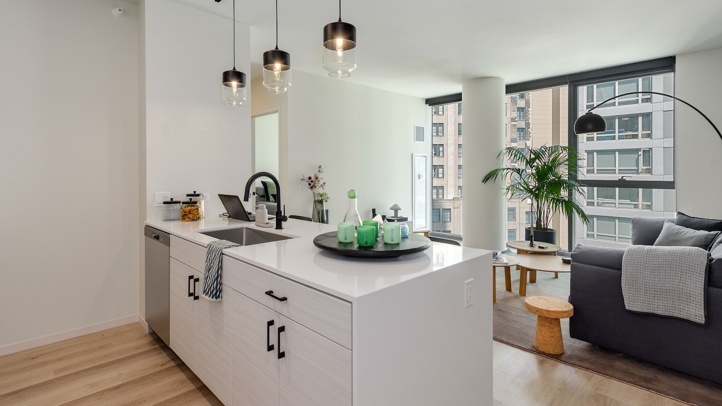 Modern kitchen island with sleek counters and pendant lights, overlooking a stylish living area at Millie on Michigan Chicago