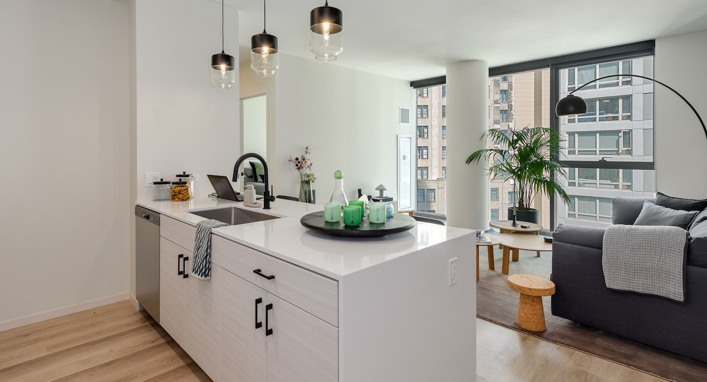 Modern kitchen island with sleek counters and pendant lights, overlooking a stylish living area at Millie on Michigan Chicago